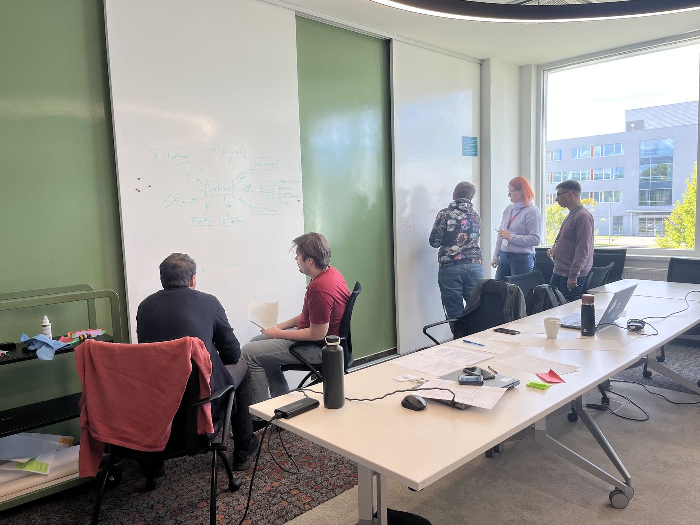 Engineers at a whiteboard sketching a system architecture during an on-site workshop
